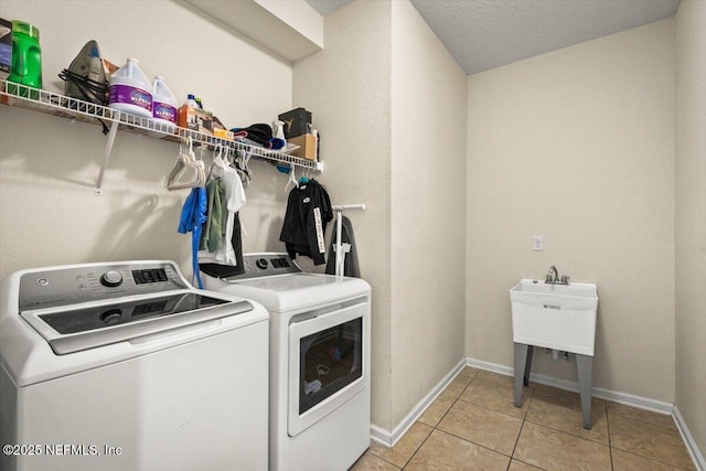 washroom with light tile patterned floors, washing machine and dryer, and a textured ceiling