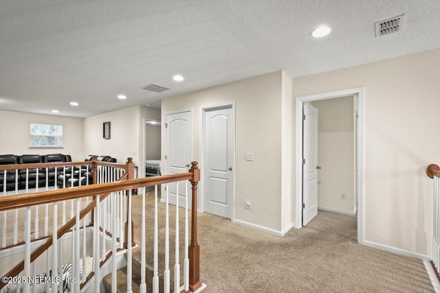 hall featuring a textured ceiling and light carpet