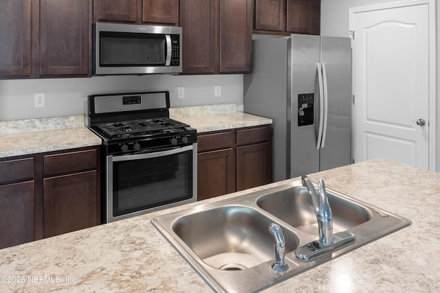 kitchen featuring dark brown cabinetry, sink, and stainless steel appliances