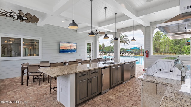 kitchen with refrigerator, a breakfast bar, dark brown cabinets, wooden walls, and decorative light fixtures