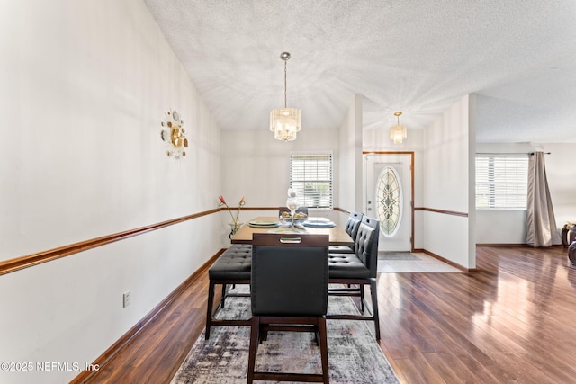 dining space featuring dark hardwood / wood-style flooring, a textured ceiling, and a chandelier