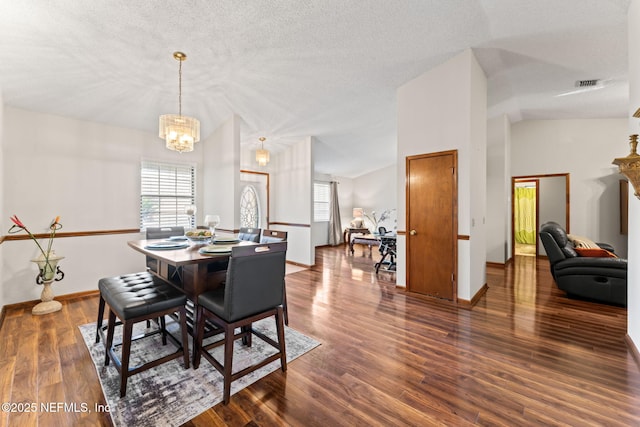 dining space featuring a textured ceiling, a chandelier, vaulted ceiling, and dark wood-type flooring