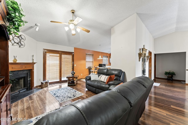 living room with ceiling fan, dark hardwood / wood-style flooring, a fireplace, a textured ceiling, and lofted ceiling