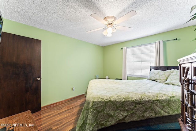 bedroom with ceiling fan, a textured ceiling, and dark hardwood / wood-style floors