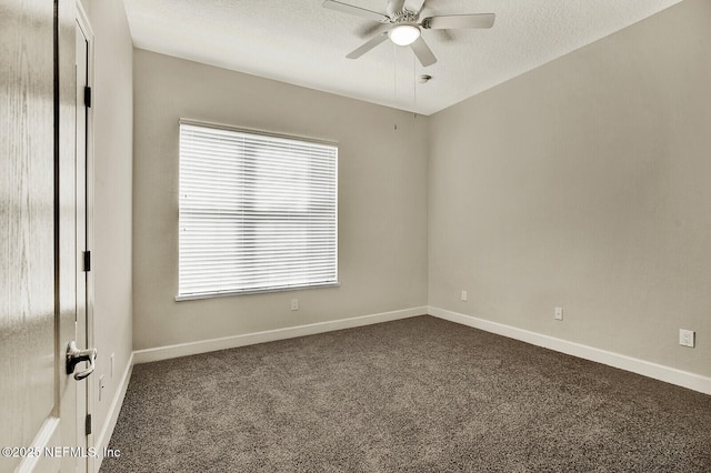 empty room with a textured ceiling, dark carpet, and ceiling fan