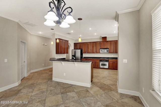 kitchen featuring stainless steel appliances, a chandelier, pendant lighting, a kitchen bar, and a kitchen island with sink