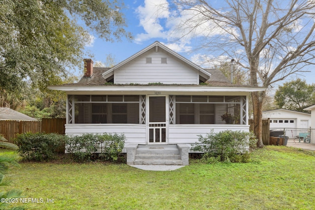 back of property featuring an outdoor structure, a yard, a sunroom, and a garage