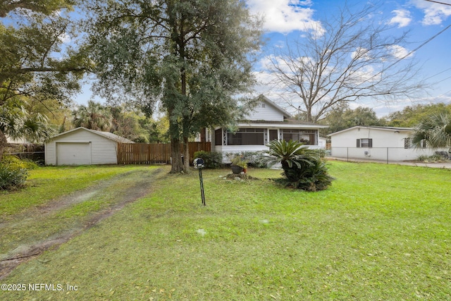 view of yard featuring a sunroom, a garage, and an outbuilding