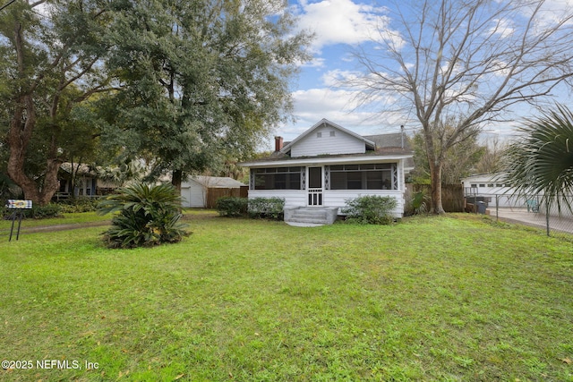 rear view of property featuring a yard, a sunroom, and a shed