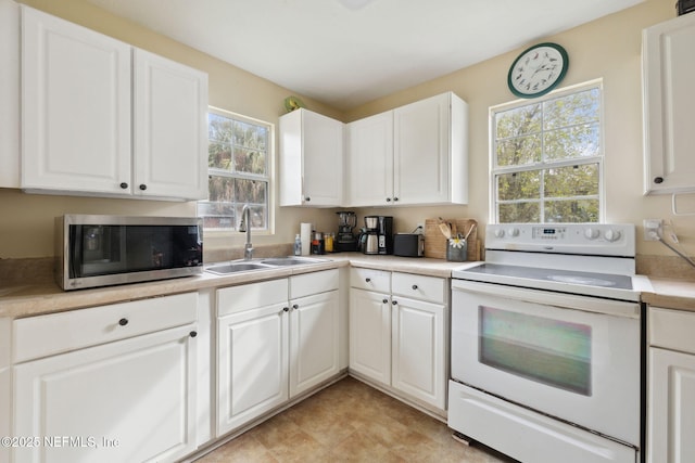 kitchen featuring electric range, white cabinetry, a healthy amount of sunlight, and sink