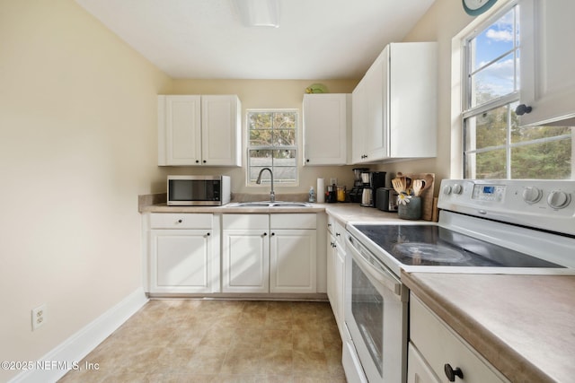 kitchen with electric range, white cabinets, and sink