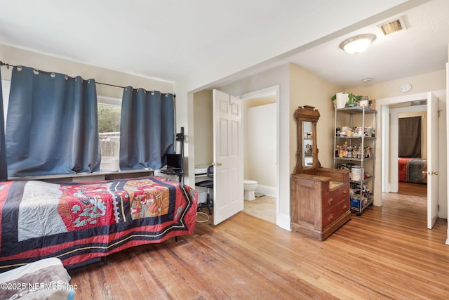 bedroom with light wood-type flooring and connected bathroom