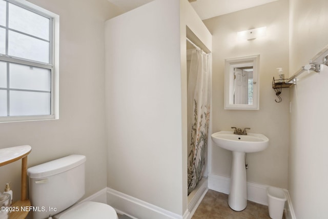 bathroom featuring toilet, a shower with shower curtain, and a wealth of natural light