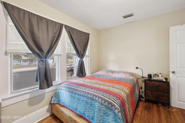 bedroom with dark wood-type flooring and multiple windows