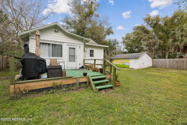 rear view of property featuring a lawn, a shed, and a wooden deck