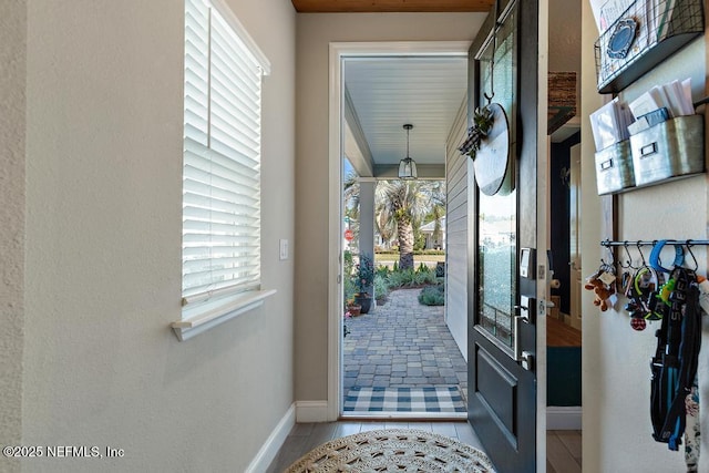 doorway with baseboards and tile patterned floors