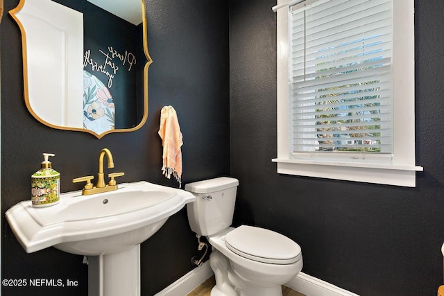 bathroom with baseboards, a sink, and toilet