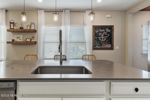 kitchen featuring dishwasher, white cabinetry, and hanging light fixtures