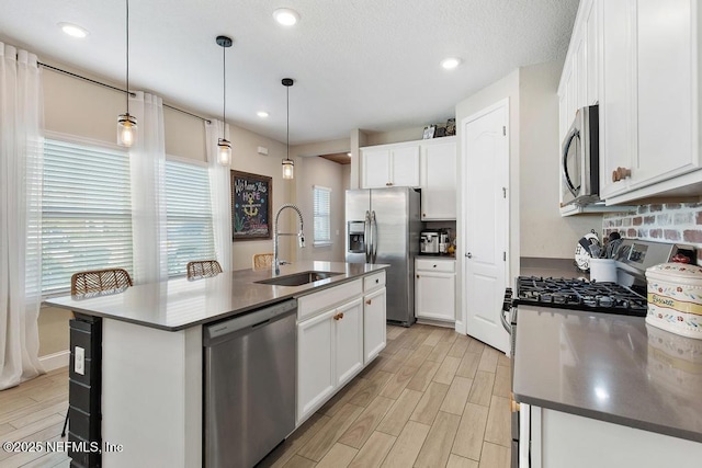 kitchen with stainless steel appliances, wood finish floors, a sink, and white cabinets