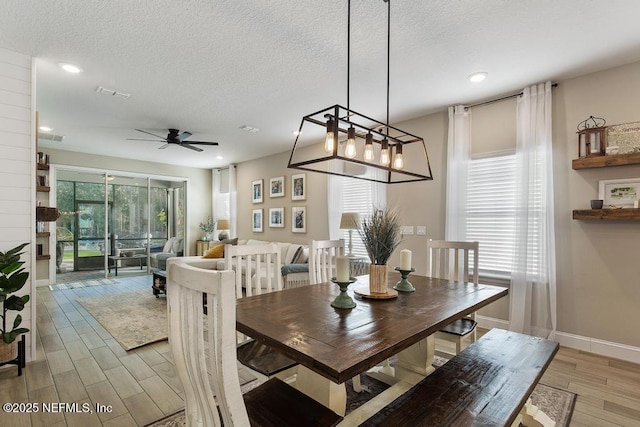 dining area featuring light wood-style floors, visible vents, plenty of natural light, and a textured ceiling