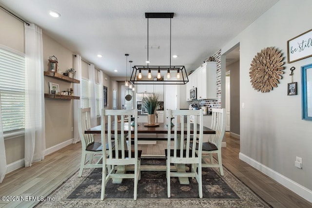 dining area featuring hardwood / wood-style flooring, a healthy amount of sunlight, a textured ceiling, and a chandelier