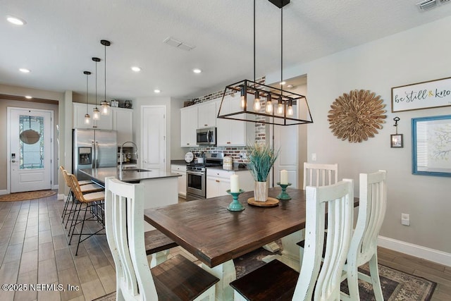 dining space featuring light wood-type flooring, visible vents, and baseboards