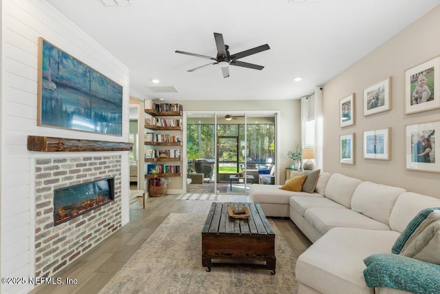 living room featuring light wood-type flooring, a brick fireplace, and ceiling fan