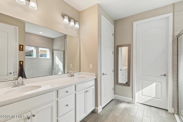 bathroom featuring a stall shower, a sink, baseboards, and double vanity