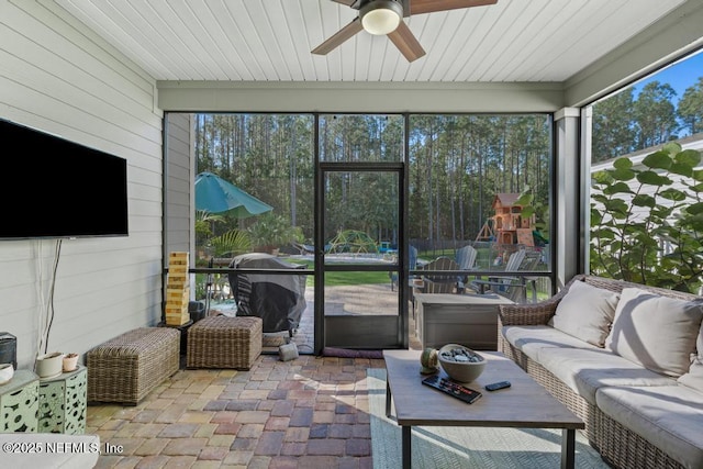 sunroom / solarium with a ceiling fan, a wealth of natural light, and wood ceiling