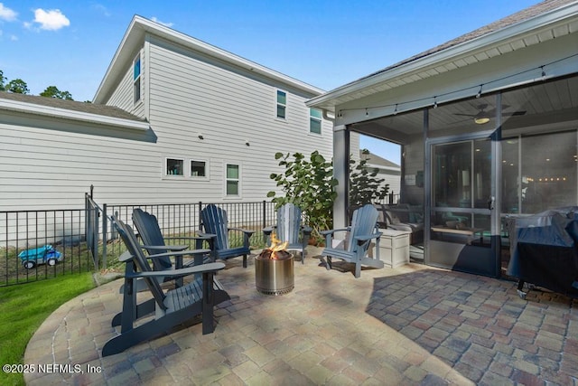 view of patio / terrace with a fire pit, a sunroom, and ceiling fan