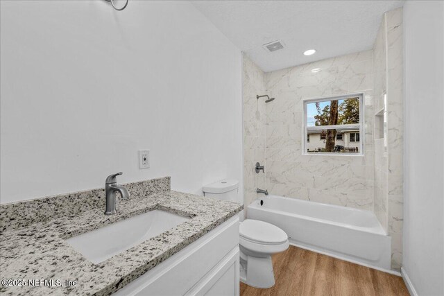 full bathroom with toilet, hardwood / wood-style flooring, tiled shower / bath, and vanity