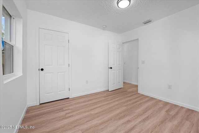 unfurnished bedroom featuring a textured ceiling and light hardwood / wood-style flooring