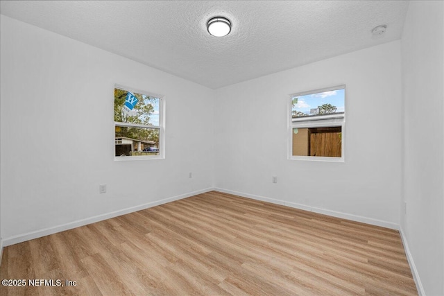 spare room featuring a textured ceiling, light wood-type flooring, and a wealth of natural light