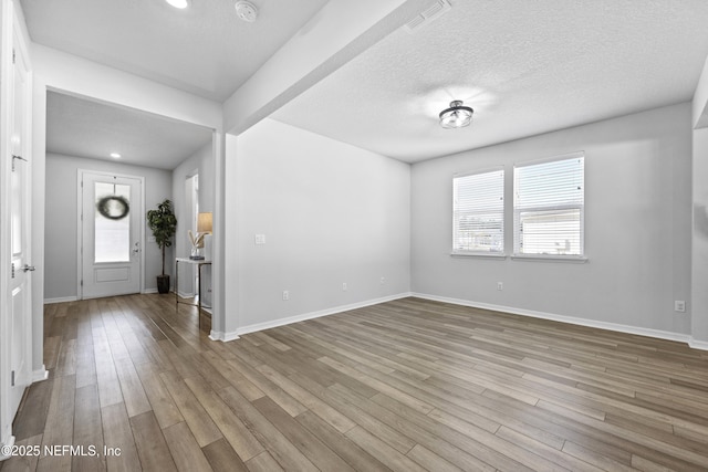 foyer with light wood-type flooring and a textured ceiling