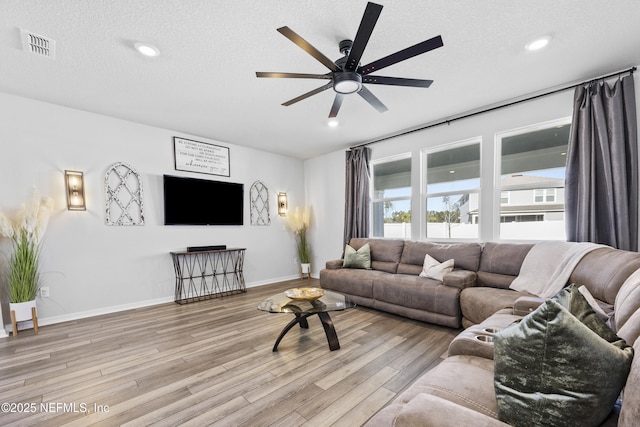 living room featuring ceiling fan, a textured ceiling, and light hardwood / wood-style flooring