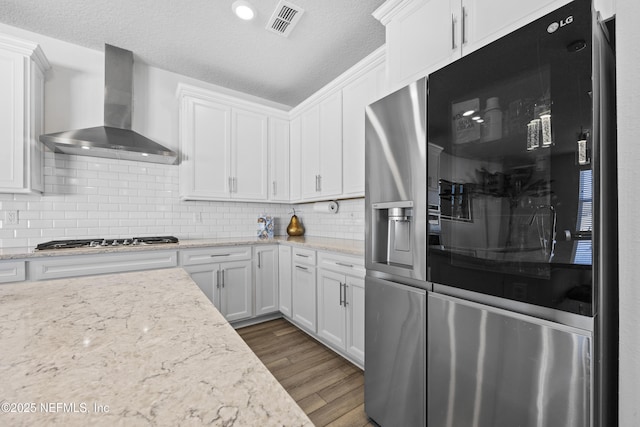 kitchen with white cabinetry, wall chimney range hood, stainless steel appliances, tasteful backsplash, and dark hardwood / wood-style floors