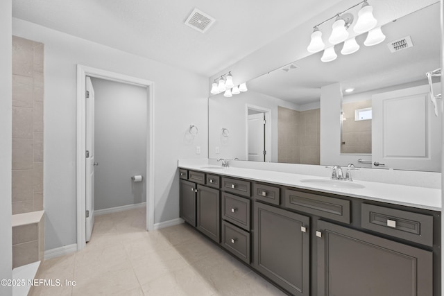 bathroom with vanity, tile patterned flooring, and a tile shower