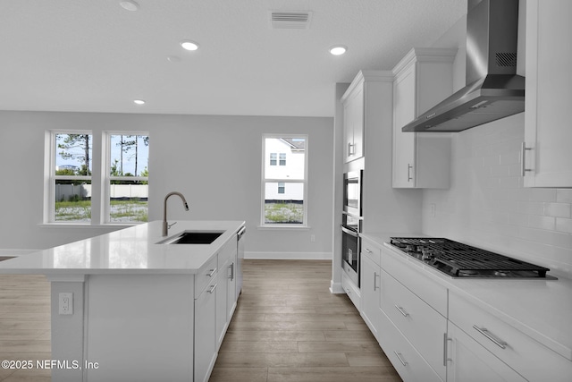 374 Sutton Dr, Ponte Vedra, FL 32081 - kitchen with wall chimney range hood, appliances with stainless steel finishes, decorative backsplash, light countertops, and a kitchen island with sink