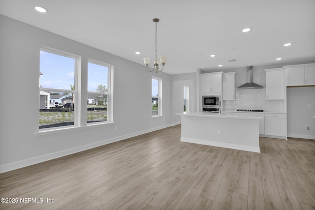 374 Sutton Dr, Ponte Vedra, FL 32081 - kitchen with wall chimney range hood, stainless steel appliances, light wood-style floors, white cabinetry, and recessed lighting