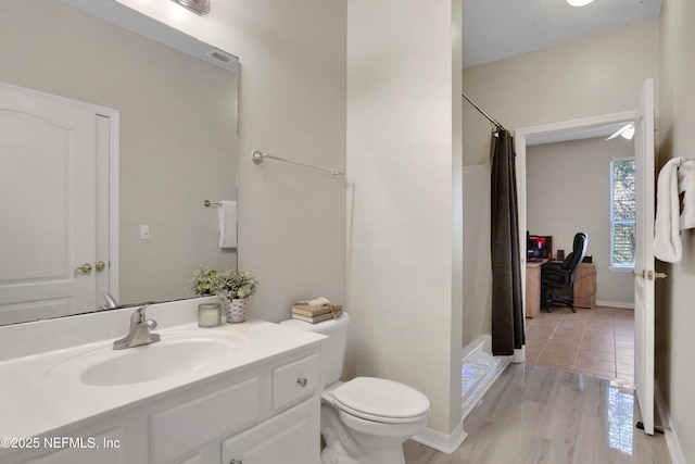 bathroom with hardwood / wood-style flooring, vanity, toilet, and walk in shower