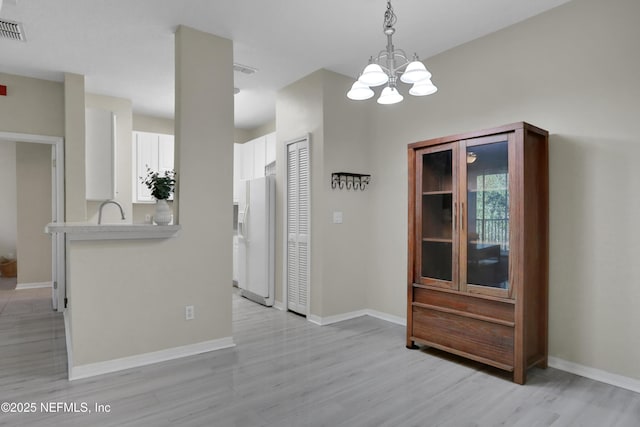 unfurnished dining area with light hardwood / wood-style floors, a notable chandelier, and sink