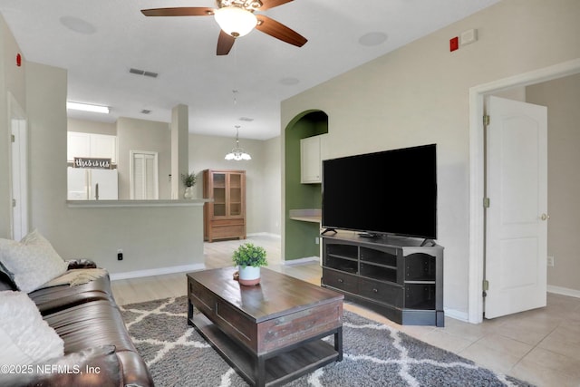 tiled living room featuring ceiling fan with notable chandelier