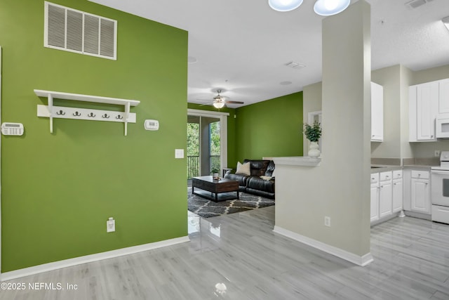 interior space featuring white cabinets, ceiling fan, white appliances, and light hardwood / wood-style flooring