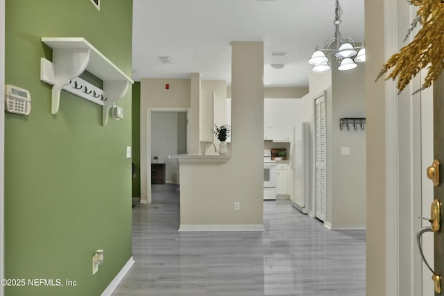 corridor with light hardwood / wood-style flooring and a chandelier