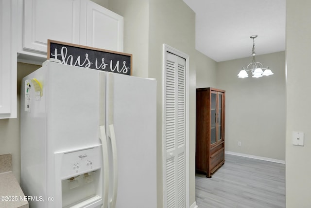 kitchen featuring pendant lighting, an inviting chandelier, white cabinetry, and white fridge with ice dispenser