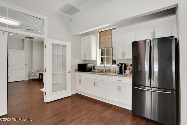 kitchen featuring stainless steel refrigerator, light stone countertops, sink, and white cabinets