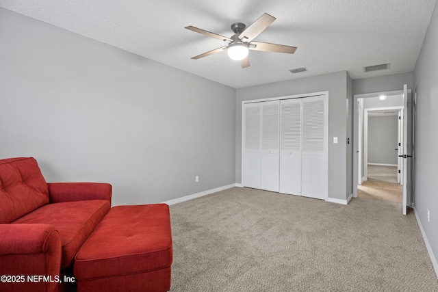 sitting room featuring ceiling fan, light colored carpet, and a textured ceiling