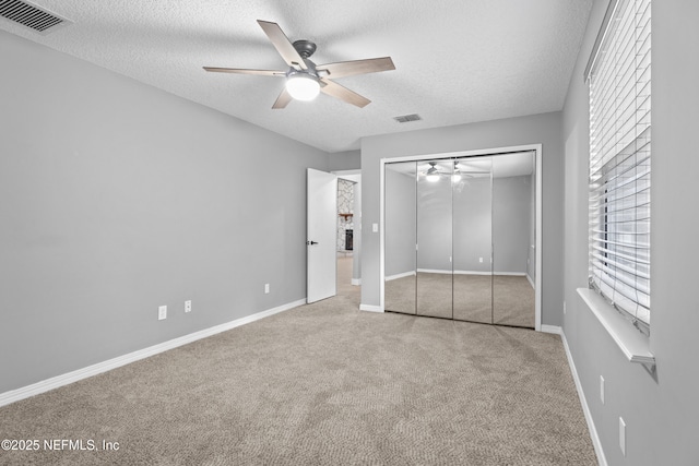 unfurnished bedroom with light carpet, a closet, ceiling fan, and a textured ceiling