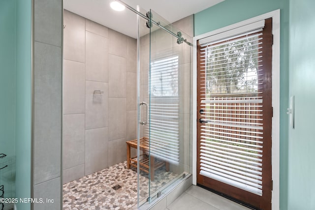 bathroom featuring a wealth of natural light, tile patterned floors, and a shower with shower door