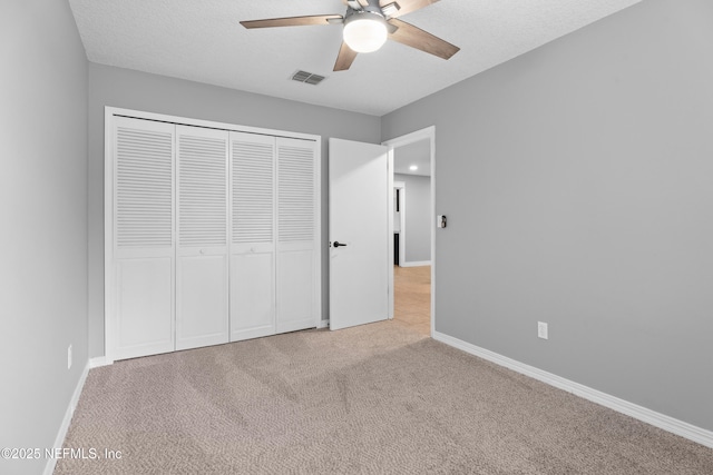 unfurnished bedroom with light carpet, a closet, ceiling fan, and a textured ceiling